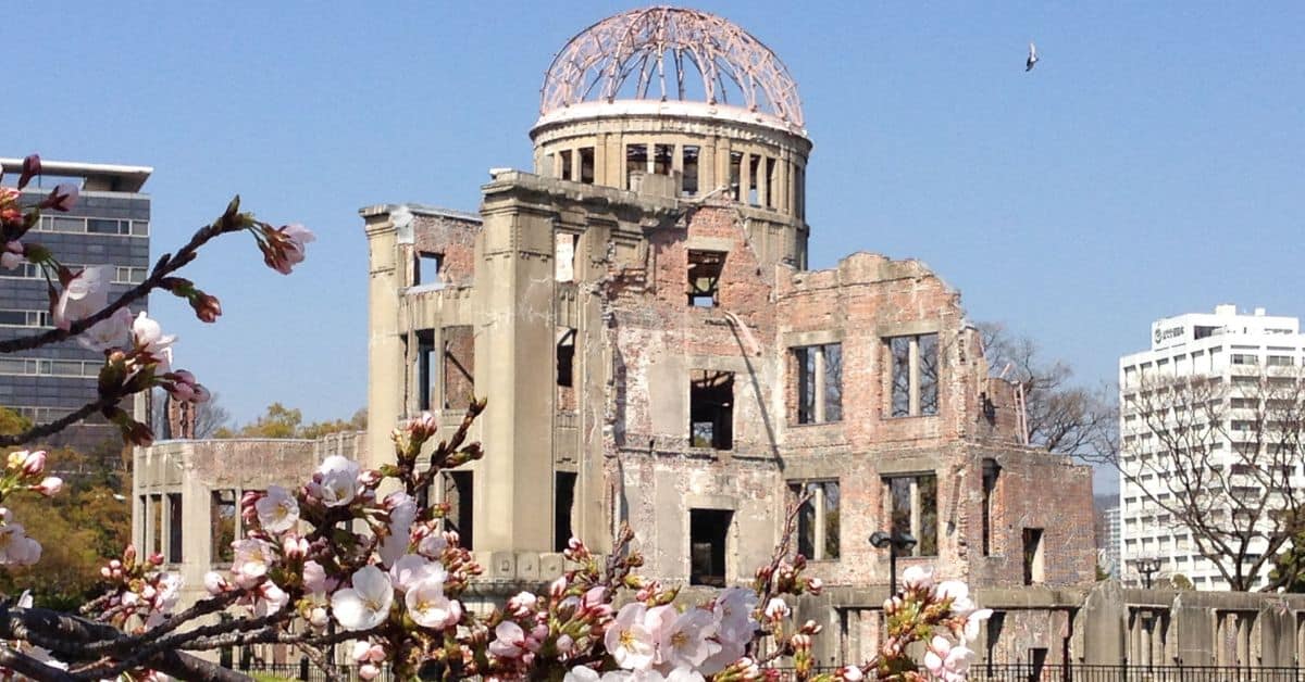The remains of the Hiroshima Prefectural Industrial Promotion Hall in Hiroshima. In the foreground are cherry blossoms.